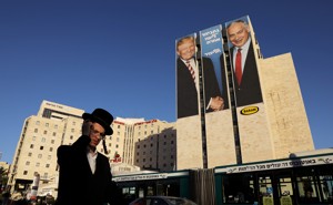 A man in Jerusalem walks past a Likud election-campaign billboard depicting President Donald Trump shaking hands with Israeli Prime Minister Benjamin Netanyahu.